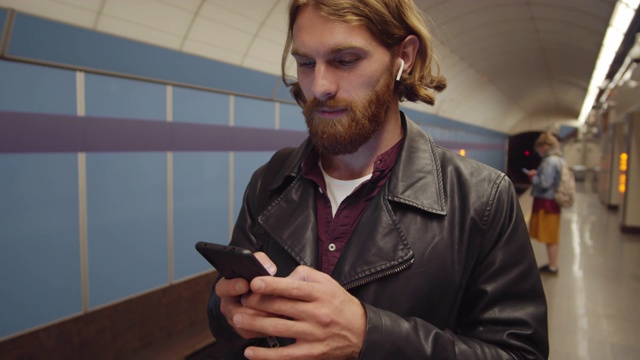 红发男在地铁站使用智能手机视频素材