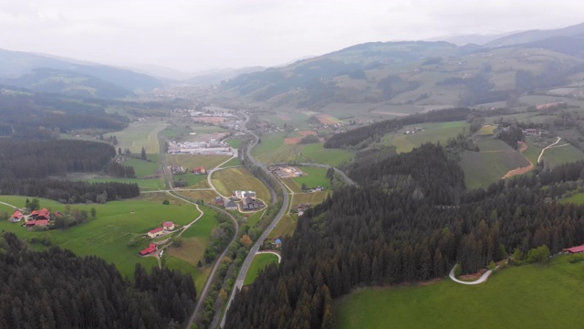 在雾天里飞过奥地利绿色山丘上的一个小村庄视频素材