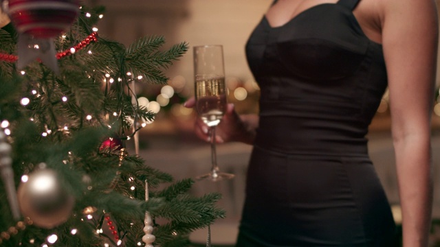 美丽的女人在圣诞花环灯下喝香槟视频素材