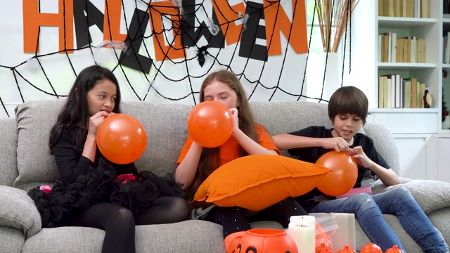孩子们，男孩和女孩们，都在吹气球来准备万圣节派对的装饰视频素材