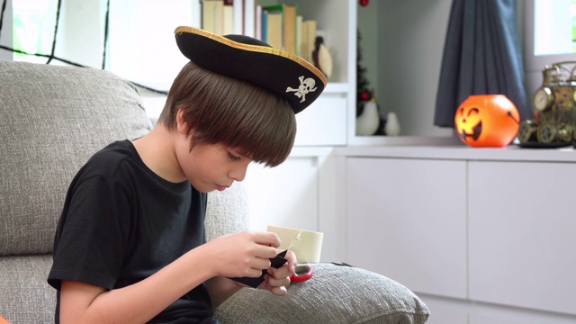 一个带着海盗帽的小男孩正在用纸工艺品来准备万圣节派对装饰视频素材