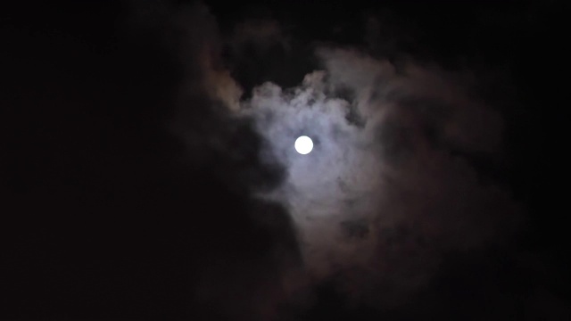 《满月穿过乌云在夜空中移动》4k镜头，延时。神秘的月亮在云从闪亮到完全被乌云覆盖。月光照耀着漆黑的夜空。视频素材