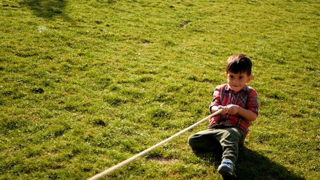 一个男孩在公园里拉绳子玩拔河游戏视频下载