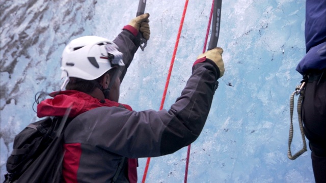 冰上攀岩者使用冰爪、绳索和鹤嘴锄在冰墙中穿行。视频素材