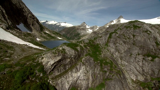 陡峭的岩石山峰环绕着一个小的山湖。视频下载