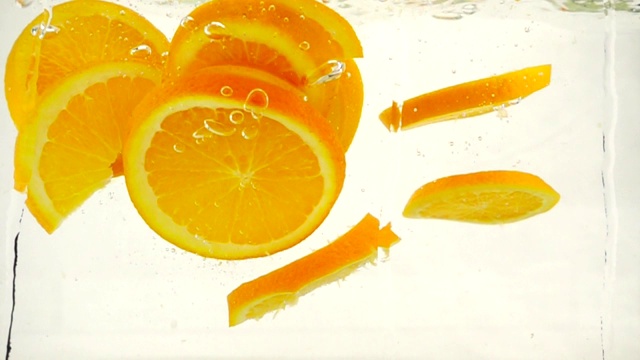 多汁的橙子片落入水中，溅起水花，冒出泡泡，慢镜头特写视频素材