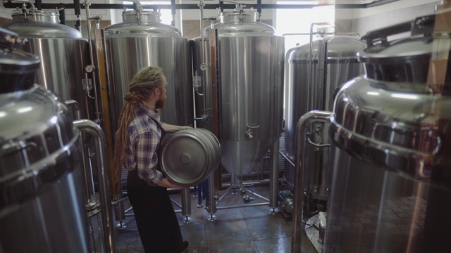 年轻男子在小型精酿啤酒制造厂工作，检查啤酒的质量。在啤酒厂工作的男性视频下载