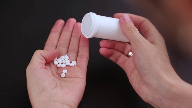 药丸从一个塑料瓶倒入一只手。视频素材