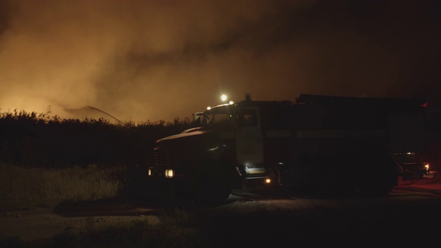 闪灯的消防车。森林大火中，消防车在草地上燃烧。自然灾害的救助和预防视频素材