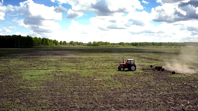 拖拉机在阳光明媚的日子里在森林里的广阔田野上播种视频下载
