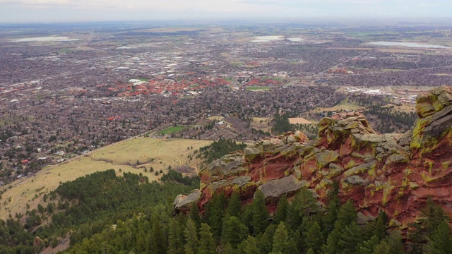 航拍:无人机在岩石山脉上移动，城市对天空-博尔德，科罗拉多州视频下载