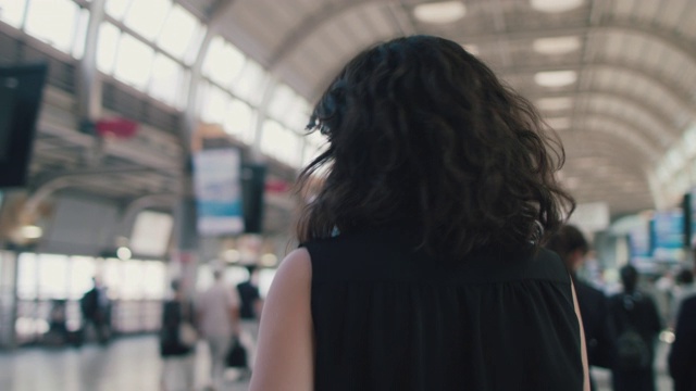 一名日本女子戴着耳机和智能手机在东京火车站转弯视频素材