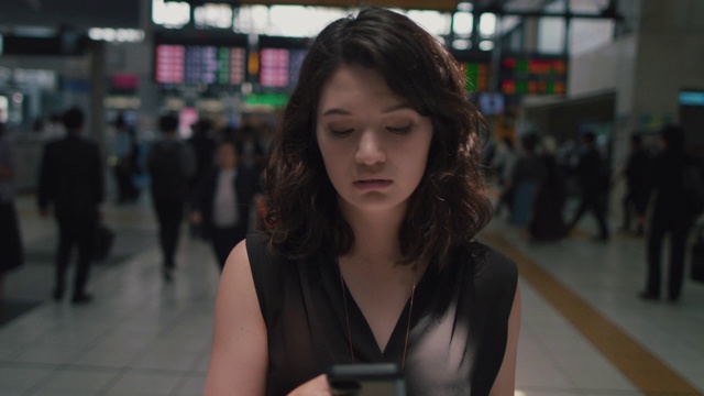 日本东京，一名日本女子在火车站里拿着电话走来走去视频素材