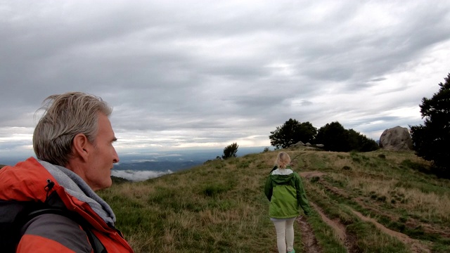 徒步旅行的夫妇沿着草地山脊散步视频素材