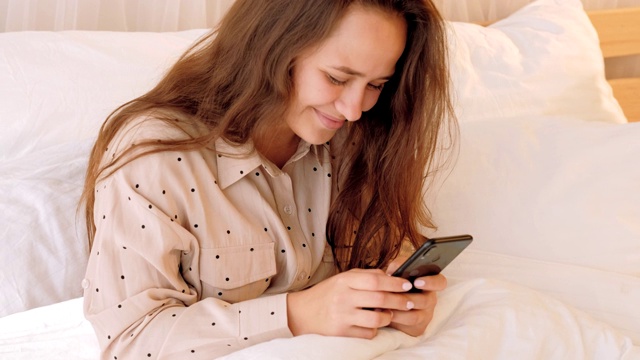 少女在家里的床上使用智能手机视频素材