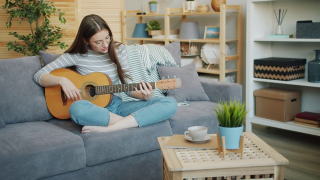 一个漂亮女孩独自在家弹吉他的慢镜头视频素材