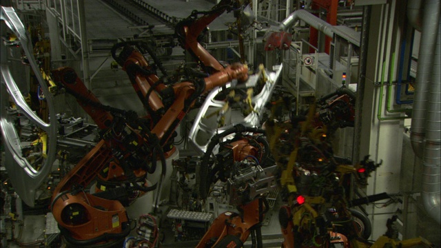在宝马工厂，装配线上的机器人在不同的汽车零件上旋转和工作。视频素材