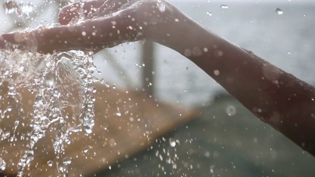 清澈的水流入一个女人的手中。缓慢的运动。视频下载