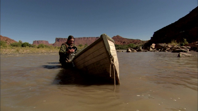 探险家用帽子把木船里的水舀出来。视频下载