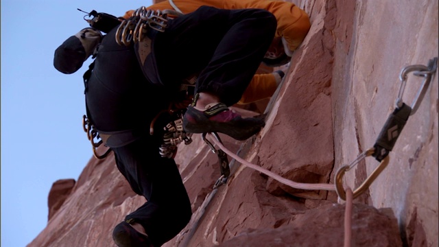 一名攀岩者小心翼翼地爬上悬崖。视频素材