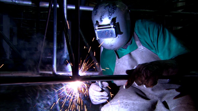 一名焊工连接一个金属框架，然后放下面罩开始工作。视频下载