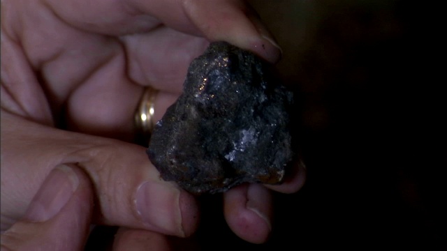 一个地质学家拿着一块铅岩石。视频下载