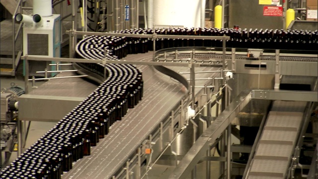 在工厂里，成千上万的啤酒瓶在传送带上移动。视频素材