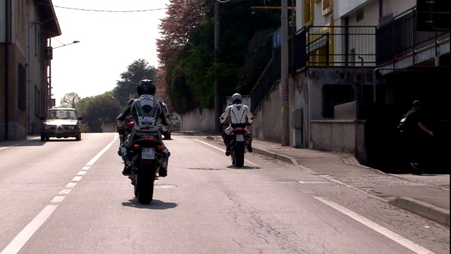 骑摩托车的人穿过一个城镇。视频素材