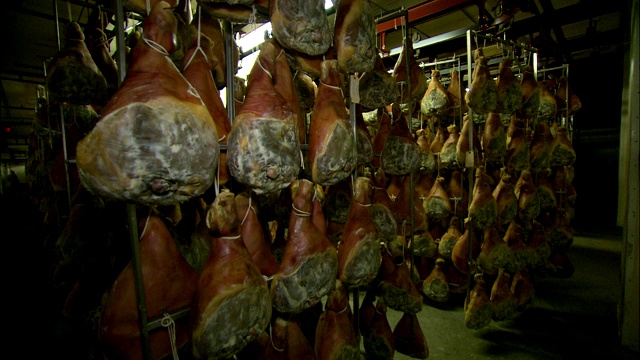 熏火腿挂在猪肉加工厂的架子上。视频下载
