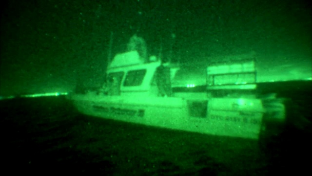 晚上，两个人站在一艘渔船的桥上。视频下载