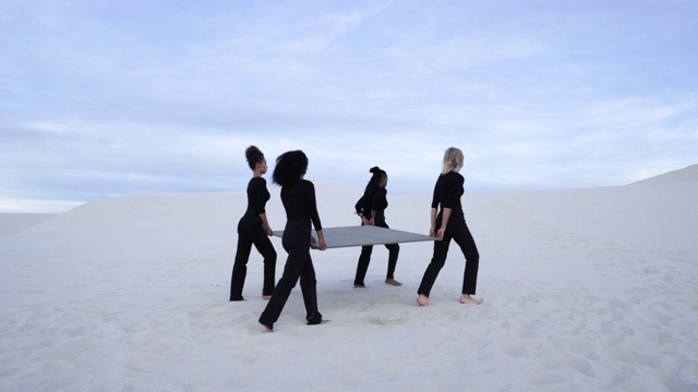 中景，四个女人在沙漠中手持灰色传送门视频素材