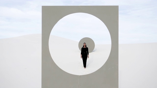 Woman walks up to placard with circle window frame in desert视频素材
