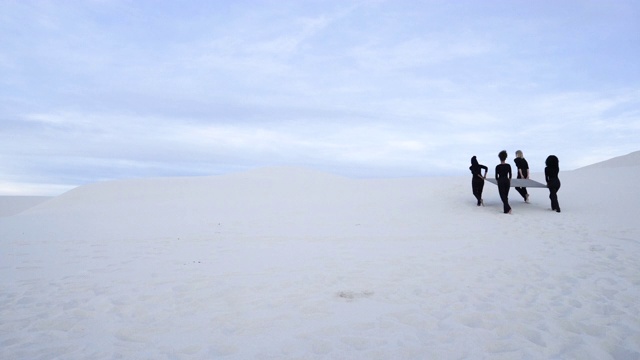 四名妇女在沙漠中举起灰色方块，中镜头视频素材