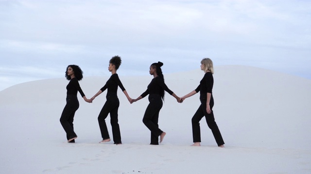 不同的黑人妇女在沙漠中手拉手视频素材