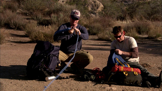 两个攀岩者在沙漠中准备他们的装备。视频下载