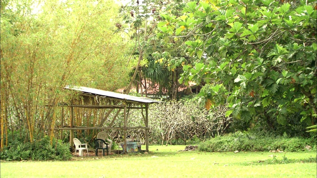 一个金属遮阳篷覆盖着树木繁茂地区的草坪家具。视频下载