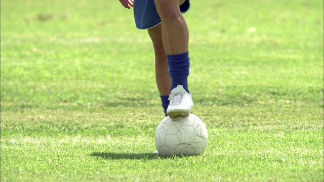 一名运动员把脚放在草地上的足球上。视频素材