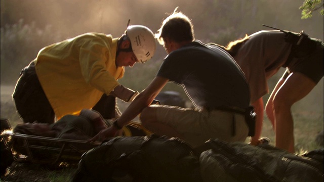 医护人员为躺在担架上的受伤徒步旅行者绑上带子。视频下载