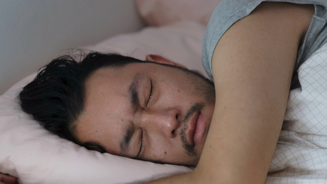 特写的年轻亚洲男子睡眠不好，失眠躺在床上视频下载
