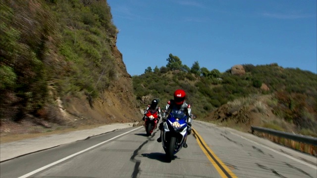 两个摩托车手在一条蜿蜒的山路上行驶。视频下载