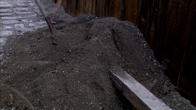 在重现伦敦下水道建设的场景中，一堆泥土和工具躺在一条砖路上。视频素材