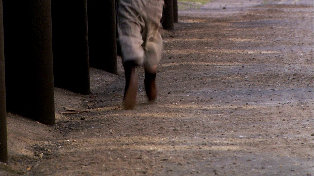 19世纪的伦敦，一个小男孩在一条鹅卵石街道上奔跑。视频素材