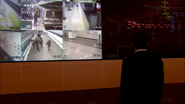 一名指挥员在控制室的墙上看着巨大的监视器。视频素材