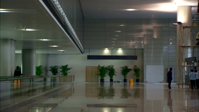 建筑工人站在脚手架上，在机场候机楼的柱子上作画。视频下载
