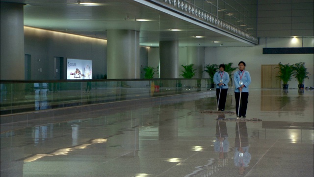 在上海虹桥交通枢纽，保管员正在清扫光滑的地板。视频下载