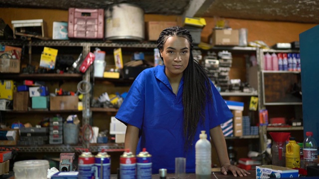 一个女机修工站在一个汽车修理店的柜台后面的肖像视频下载