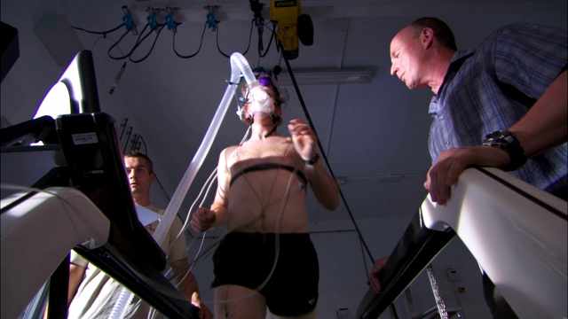一名技术人员与在跑步机上跑步的病人交流。视频下载