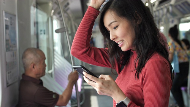 一名亚洲女性在火车上使用智能手机视频素材