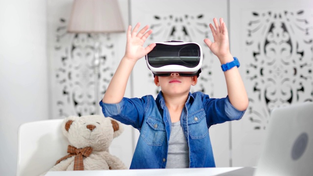 热情洋溢的小男孩戴着虚拟现实头盔，在网络空间中做手势视频下载