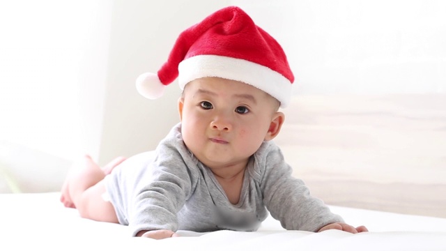 亚洲小男孩戴着圣诞老人帽。圣诞快乐，我是小圣诞老人。三个月大视频下载